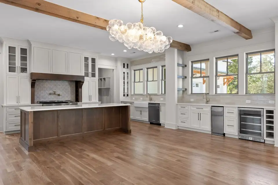 Custom cabinets in Soddy-Daisy, TN: white inset kitchen cabinets with glass uppers, a stained wood island, wood range hood and wood beams
